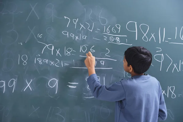 Boy working at chalkboard — Stock Photo, Image