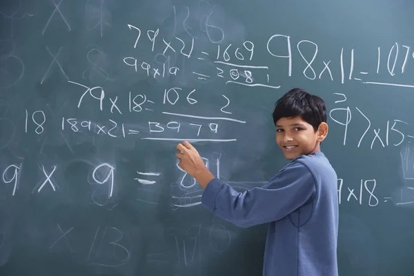 Boy working at chalkboard — Stock Photo, Image