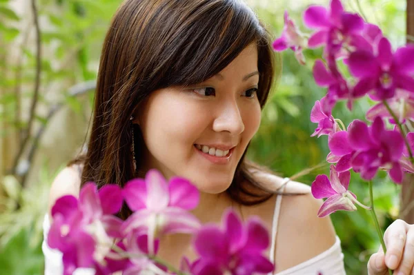 Mulher olhando para orquídeas — Fotografia de Stock