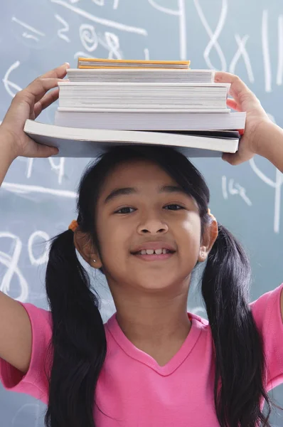 Chica con libros apilados en la cabeza —  Fotos de Stock