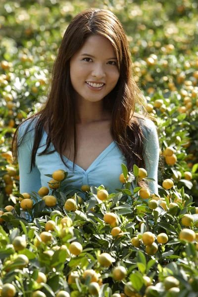 Jovem mulher entre plantas de laranja — Fotografia de Stock