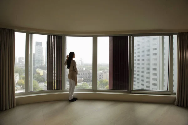 Γυναίκα ψάχνει έξω μεγάλα παράθυρα — Φωτογραφία Αρχείου