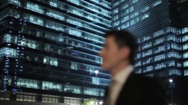 İşadamı gülen aydınlatmalı binaları önünde