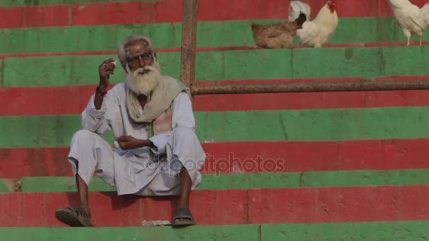 Oudere Indiase man zit op de kleurrijke stappen — Stockvideo