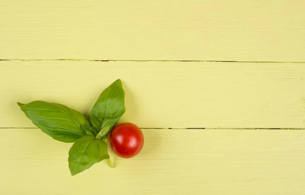 Liście bazylii i pomidorów na stole żółty — Zdjęcie stockowe