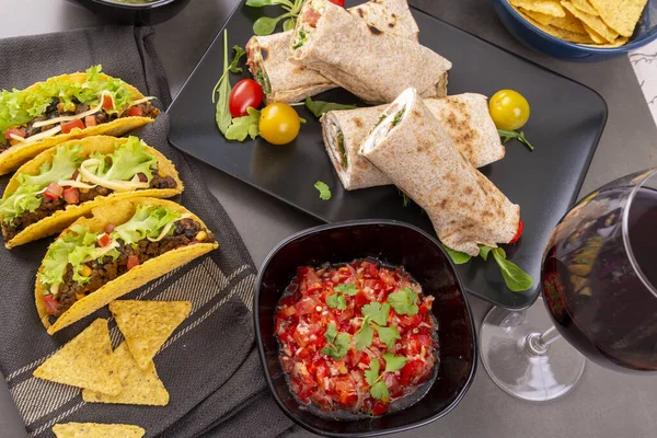 Çeşitli karışık Meksika yemekleri. Taco, burrito, fajita, salsa, karanlık bir masada nachos. Yukarıdan görüntüle