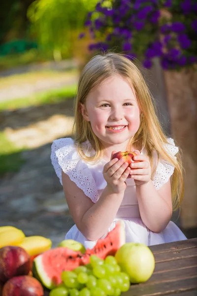 Ovocný úsměv dívku jíst vitamín v podobě nektarinek. — Stock fotografie