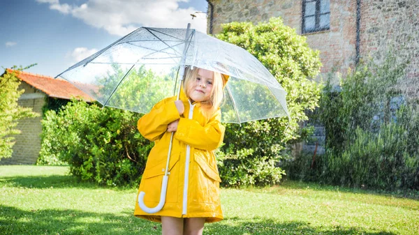 Beautiful blond girl plays with the rainy weather. — Stock Photo, Image