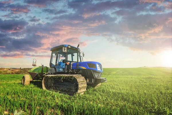 Tracteur sur les pistes dans la journée ensoleillée d'été sur un champ vert . — Photo