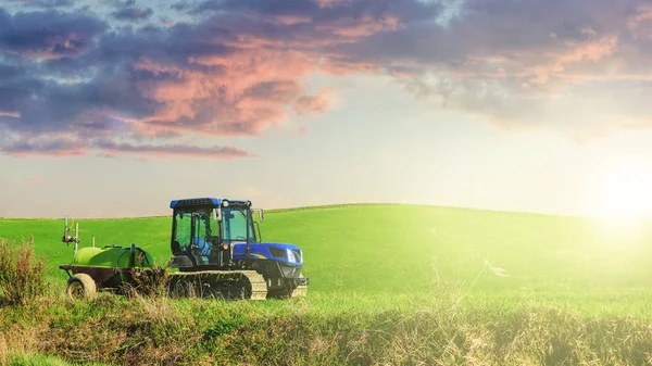 Traktor na stopách v letní slunečný den na zelené louce. — Stock fotografie