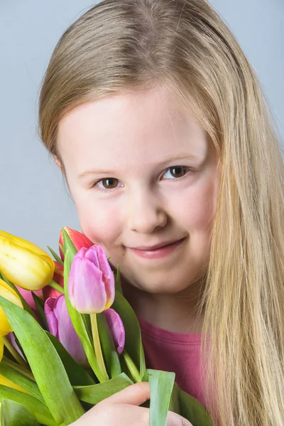 Usmívající se blondýnka s kyticí tulipánů. — Stock fotografie