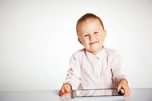 Милая маленькая и улыбающаяся девочка играет с планшетом — стоковое фото