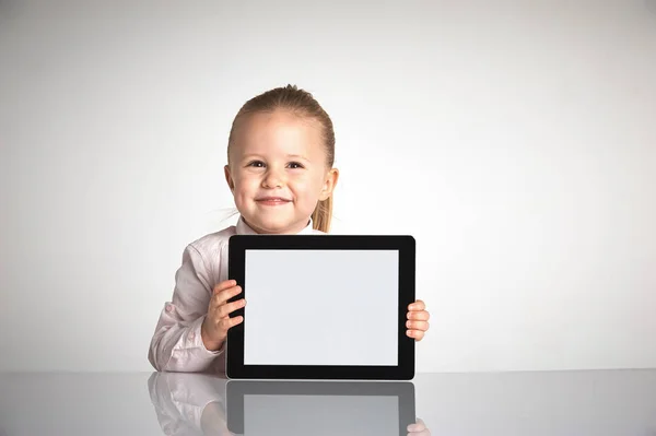 Petite fille mignonne et souriante joue avec une tablette — Photo