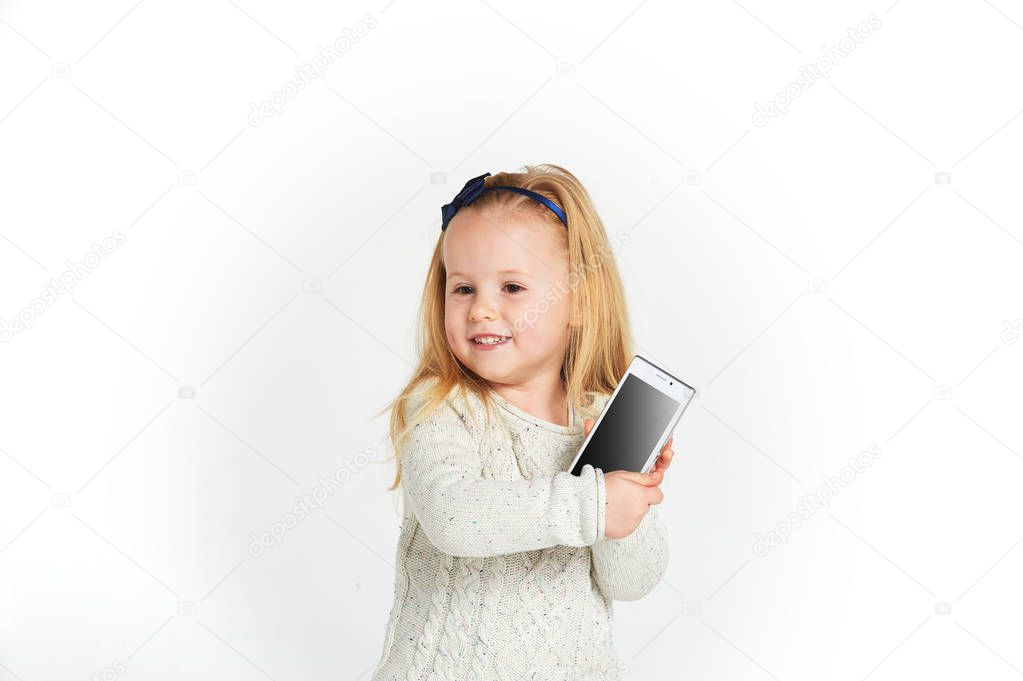 Cute little girl smiling and uses a smartphone, phone.