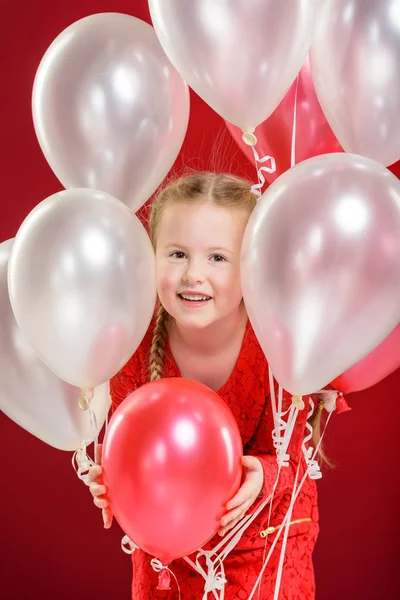 Party balloons in red, blond girl plays with. — Stock Photo, Image
