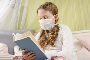 Karantina sırasında yatakta kitap okuyan bir kız..