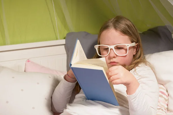 Beautiful girl with glasses, sick in bed reading a book
