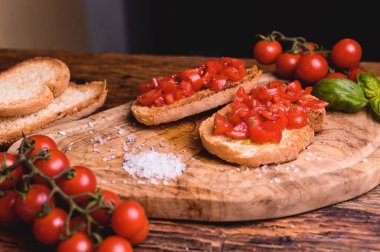 İtalyan bruschetta, taze domatesle kızartılmış ve fesleğenli ahşap masa.