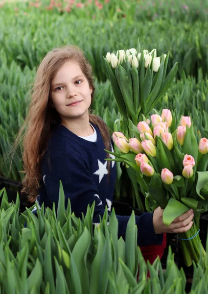 女孩拿着一束郁金香 花匠站在种植郁金香的温室里 手里拿着一束花 — 图库照片