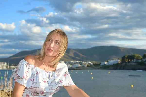 Woman sitting in front of a coastal landscape of the northern mediterranean on a summer afternoon with wind looking to the left with copy space — Stock Photo, Image