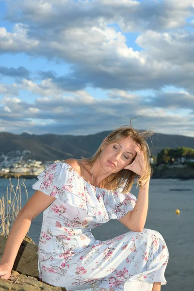 Mulher sentada em frente a uma paisagem costeira do norte do Mediterrâneo em uma tarde de verão com vento e espaço de cópia — Fotografia de Stock