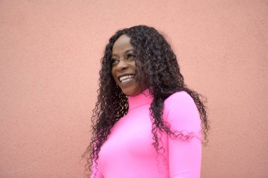 Uzun siyah kıvırcık saçlı, gülümseyen ve sola bakan mutlu bir zenci kızın portresi.