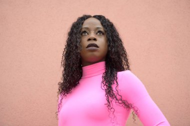 Uzun siyah kıvırcık saçlı, hayal kuran afro-stil siyah bir kızın portresi.