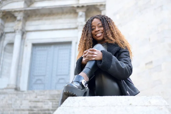 Ein fröhliches schwarzes Afro-Mädchen mit lockigem braunem Haar, das an einem bewölkten Tag in die Kamera blickt — Stockfoto