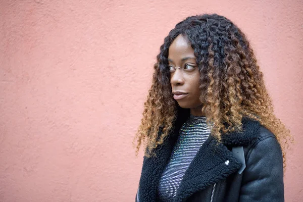 Porträt eines schwarzen Afro-Mädchens mit lockigem braunem Haar, das tagträumend nach links schaut, isoliert auf rauem Hintergrund — Stockfoto