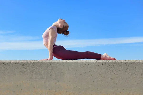 Portrait of a fit woman who practices yoga outdoors. Woman practicing asanas on a sunny day with a blue sky in the background