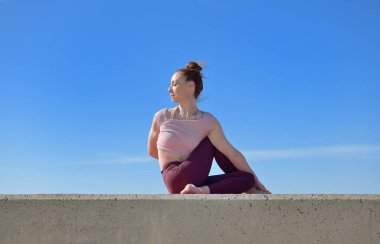 Açık havada yoga yapan sağlıklı bir kadının portresi. Güneşli bir günde arka planda mavi gökyüzü olan bir kadın asana çalışıyor.