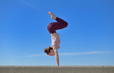 Açık havada yoga yapan sağlıklı bir kadının portresi. Güneşli bir günde arka planda mavi gökyüzü olan bir kadın asana çalışıyor.