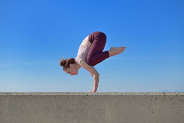 Açık havada yoga yapan sağlıklı bir kadının portresi. Güneşli bir günde arka planda mavi gökyüzü olan bir kadın asana çalışıyor.