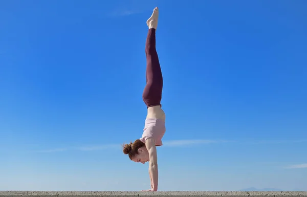 Portrait of a fit woman who practices yoga outdoors. Woman practicing asanas on a sunny day with a blue sky in the background