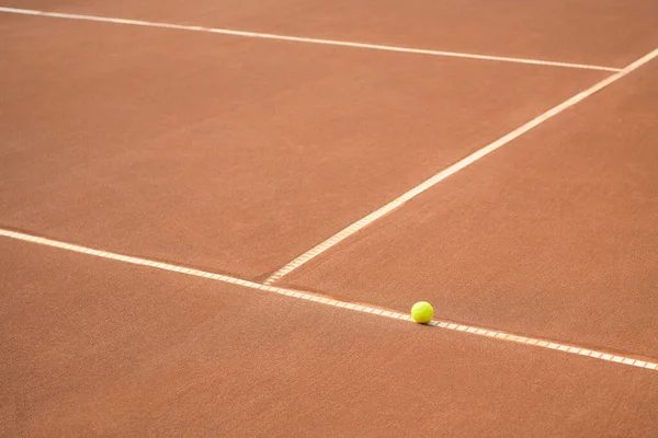 Abandoned tennis ball on a clay tennis court. Tennis ball on a line on clay tennis court. Lines on a clay tennis court. No match.