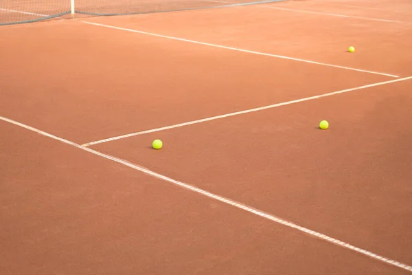 Abandoned tennis balls on a clay tennis court. Balls, lines and net on a clay tennis court. No match on the clay tennis court
