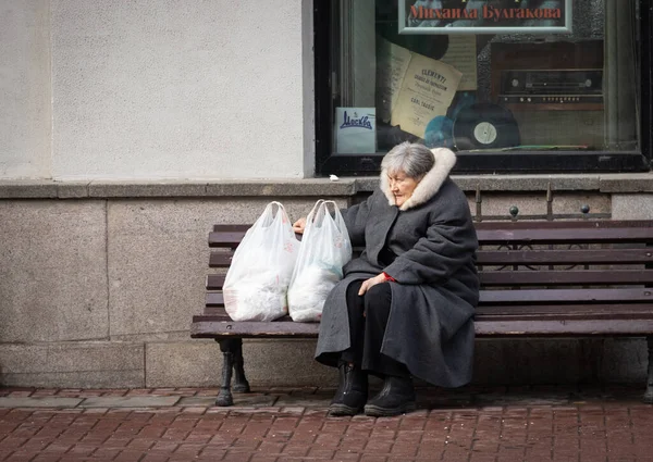 Moskova 'da Arbat' ta yaşlı bir kadın bir bankta dinleniyor. Sokak fotoğrafı.