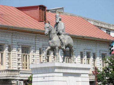 Rasht, Gilan, İran - 11 Ağustos 2019 : Rasht Belediye Meydanı'nda Rasht Belediye Binası'nda Mirza Kutschak Han'ın heykeli, kırmızı belediye binası ve mavi gökyüzü arka planı.
