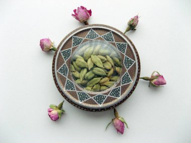 Mashhad, İran, 003 2020: Yeşil kakule podları beyaz arka planda çiçek desenli güzel el sanatları kutusuna konuldu. 