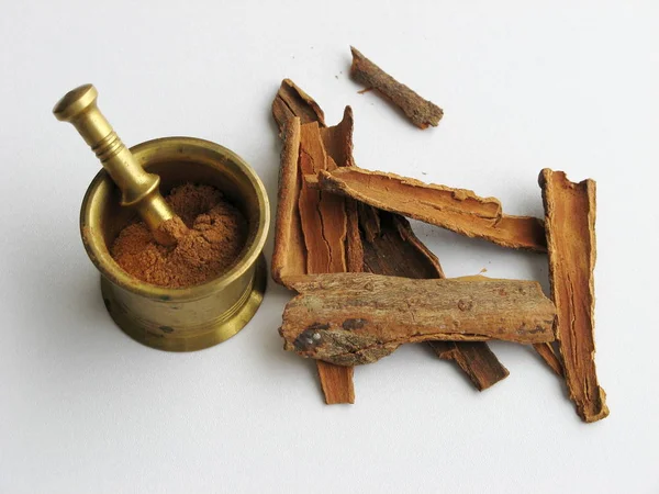 Tarçın çubuğu ezilmiş ve pirinç havanda tarçın tozu var. Çin tarçını. Cassia Tarçın. İçmek, yemek yapmak, hamur işi için baharat.