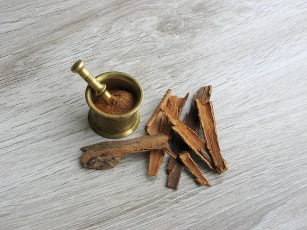 Bütün tarçın çubukları ve ezilmiş havan topu ahşap masada. Ayurveda tedavileri. Geleneksel tedavi.
