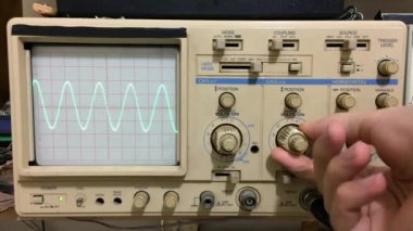 Osiloskop ile çalışan elektronik aletler ve osiloskopta gösterilen sinüs dalgası