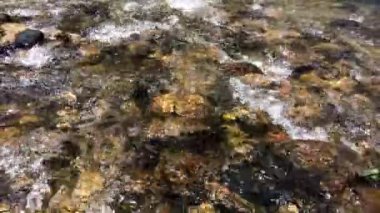 Su nehir tabanındaki kayaların arasından akar. Nehir suyu doğada akar..
