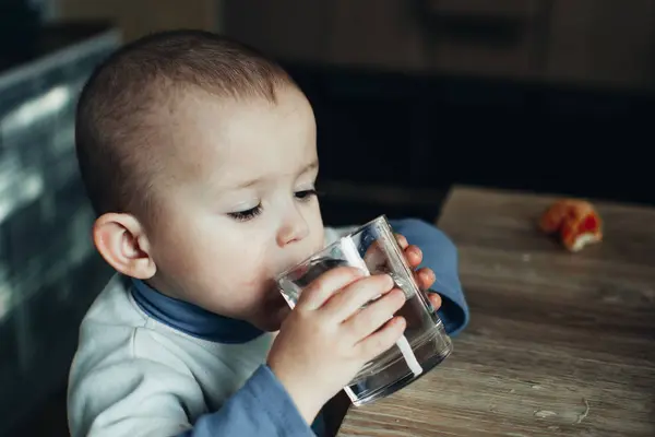 child drinks water from a glass