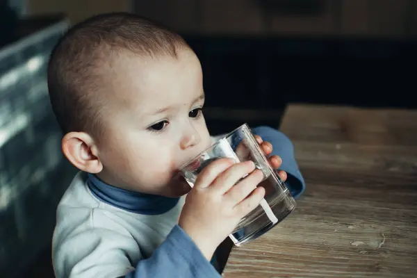 child drinks water from a glass