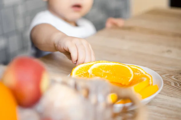 the child is reaching for an orange