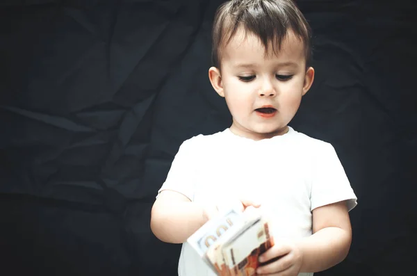 the child with the money in the hands folded on black background