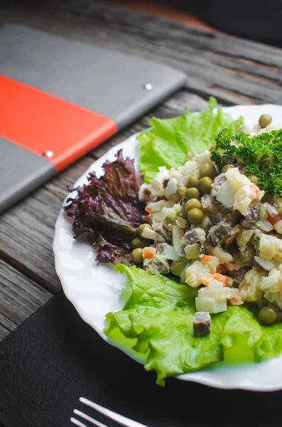 Russian winter salad, the lettuce leaf decor brown wooden background.