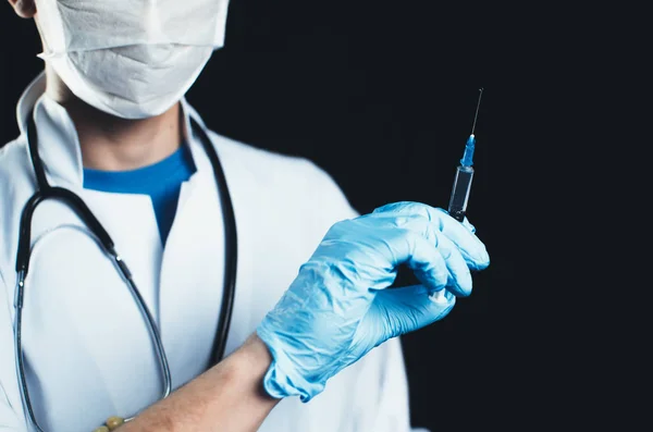 Doctor with syringe on black background with blue gloves