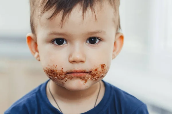 Charming child portrait, dirty face in chocolate or condensed milk